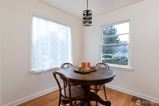 dining area featuring light wood-style floors, visible vents, and baseboards