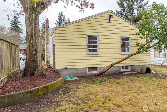 view of property exterior with a lawn and fence