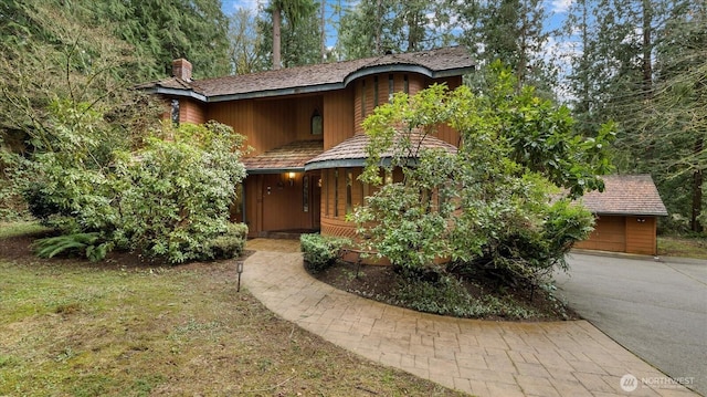 chalet / cabin featuring a chimney, driveway, and a garage