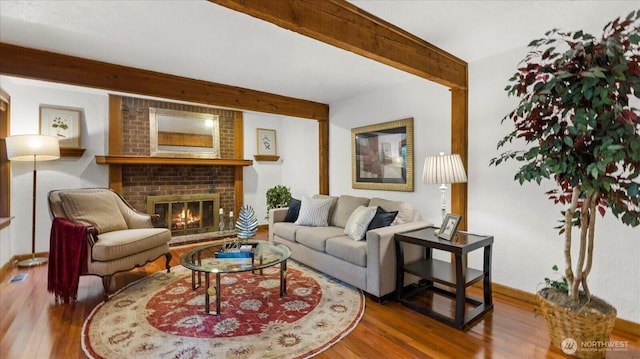 living area with a brick fireplace, beam ceiling, and wood finished floors