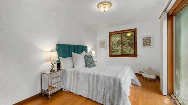 bedroom featuring wood finished floors and a textured wall