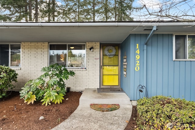 view of exterior entry featuring brick siding and board and batten siding