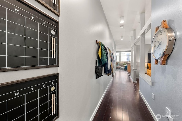 hall with dark wood-style flooring and baseboards