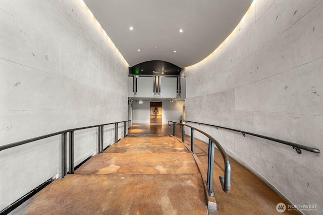 hallway featuring concrete flooring, lofted ceiling, and recessed lighting