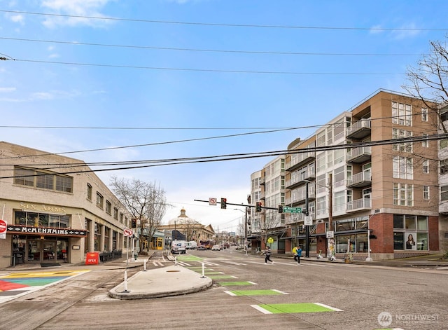 view of street featuring sidewalks, traffic lights, traffic signs, and curbs