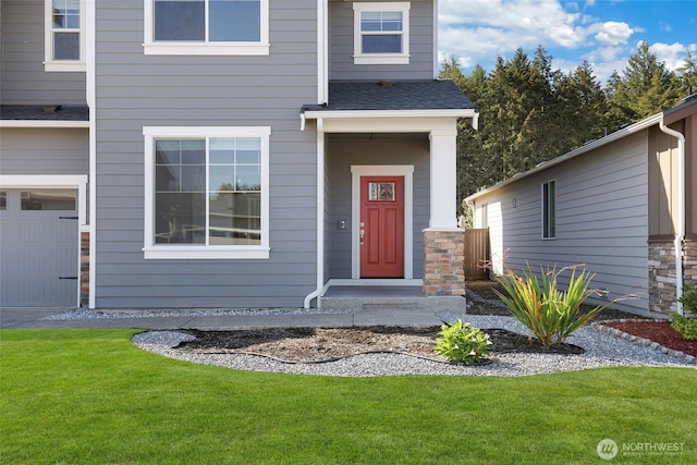 entrance to property featuring a garage, roof with shingles, and a lawn