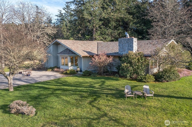 view of front of home featuring a chimney, a shingled roof, and a front yard