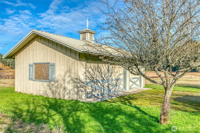view of side of home featuring an outbuilding, metal roof, a barn, and a lawn
