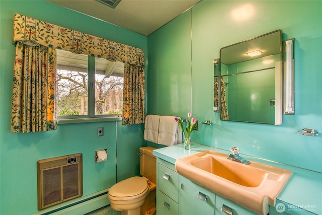 bathroom with toilet, vanity, and a baseboard heating unit