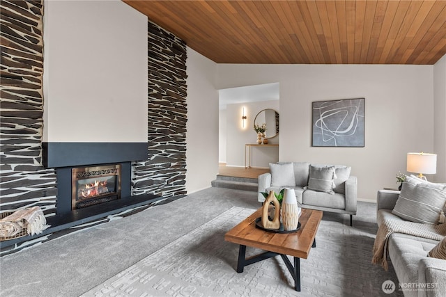 living area with a glass covered fireplace, wooden ceiling, vaulted ceiling, and carpet