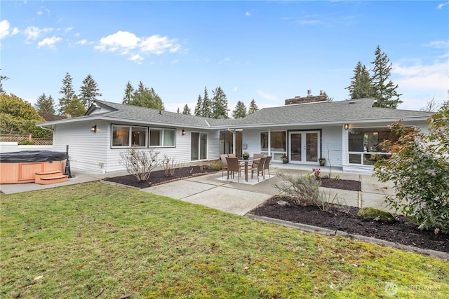 rear view of property with a shingled roof, french doors, a patio, and a hot tub