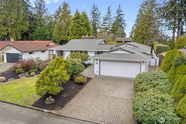 ranch-style home with decorative driveway, roof with shingles, a chimney, and an attached garage