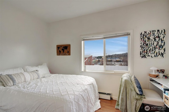 bedroom with light hardwood / wood-style floors and baseboard heating