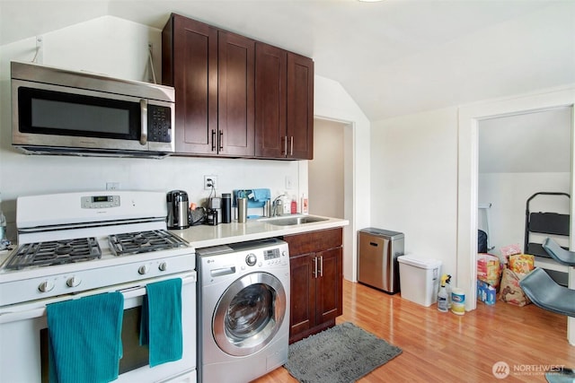 interior space featuring vaulted ceiling, sink, white range with gas cooktop, light hardwood / wood-style floors, and washer / dryer