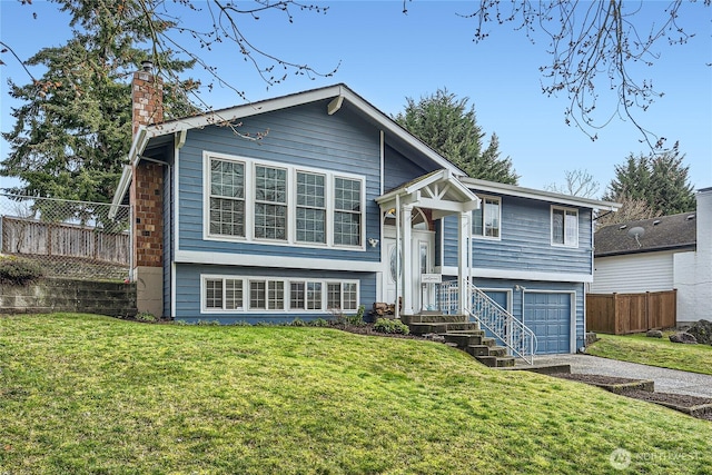 raised ranch featuring a chimney, an attached garage, a front yard, fence, and driveway