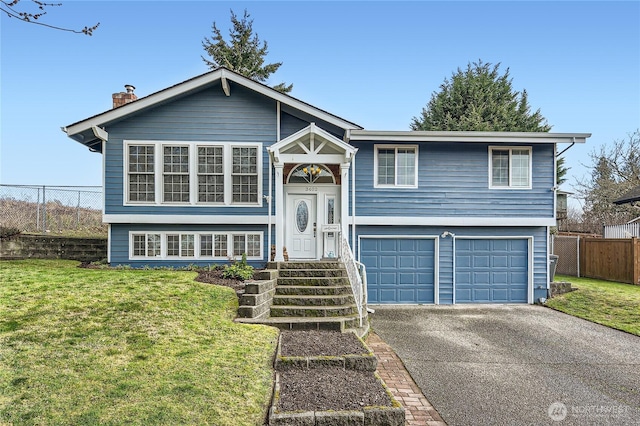 split foyer home featuring a garage, aphalt driveway, a front lawn, and fence