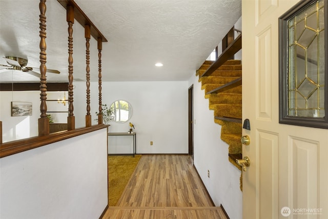 hall with recessed lighting, stairs, a textured ceiling, and wood finished floors