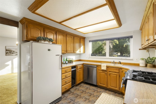 kitchen with light countertops, stainless steel dishwasher, a sink, and freestanding refrigerator