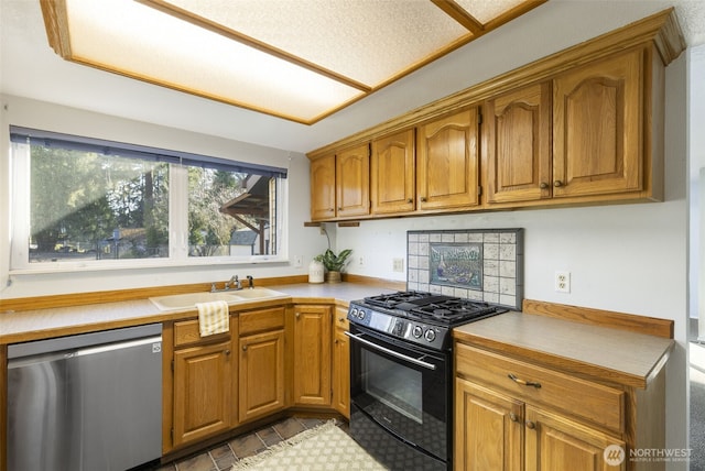 kitchen featuring light countertops, dishwasher, black gas range, and a sink