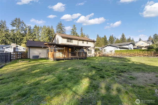 back of property with a deck, a yard, central AC, and a fenced backyard