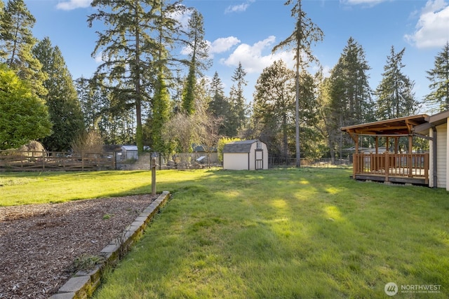 view of yard featuring an outbuilding, a fenced backyard, a wooden deck, and a storage unit