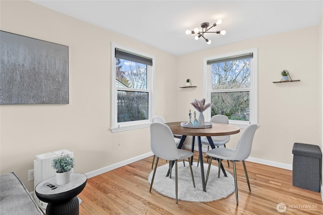 dining space with light wood-style floors, a notable chandelier, and a wealth of natural light