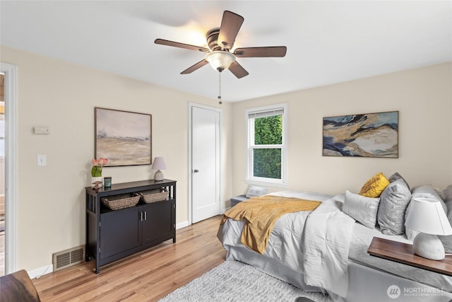 bedroom featuring light wood finished floors, baseboards, visible vents, and ceiling fan