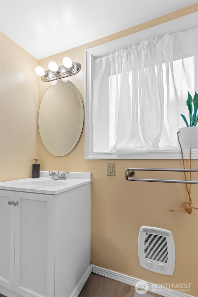 bathroom with heating unit, baseboards, wood finished floors, and vanity