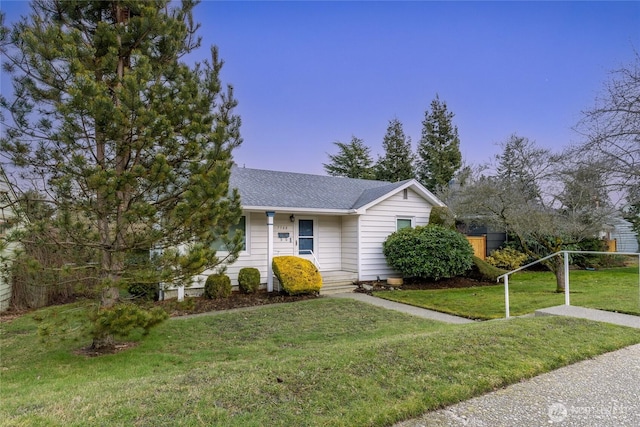 view of front of property with roof with shingles and a front yard