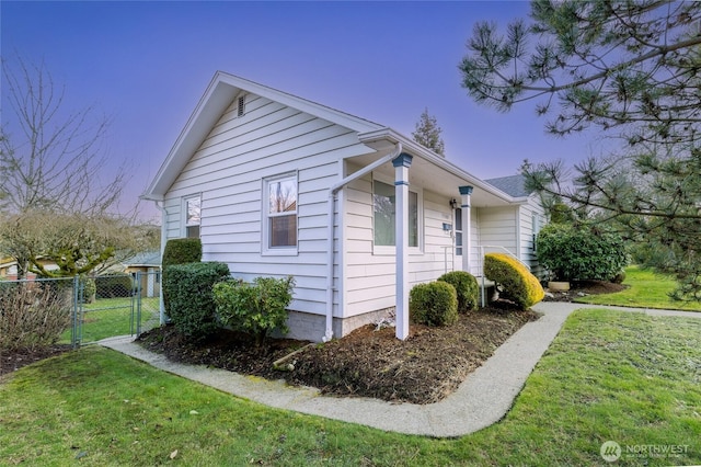 view of side of property with a yard, fence, and a gate