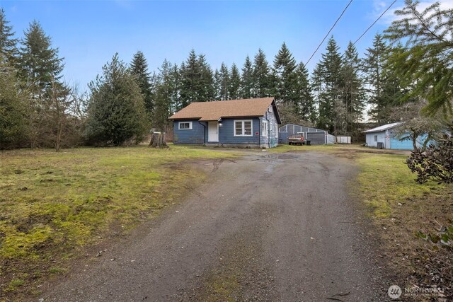 view of front of home with dirt driveway and a front lawn