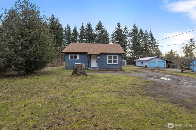 view of front of property featuring an outbuilding, a front yard, and a garage