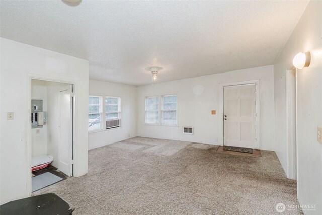 unfurnished living room featuring light carpet and a textured ceiling