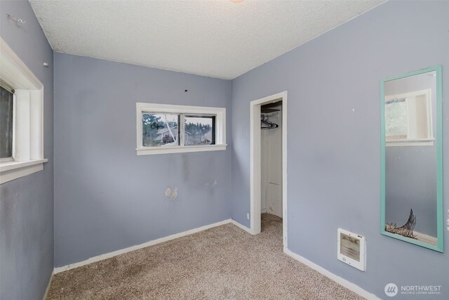 unfurnished bedroom with visible vents, light colored carpet, a spacious closet, a textured ceiling, and baseboards