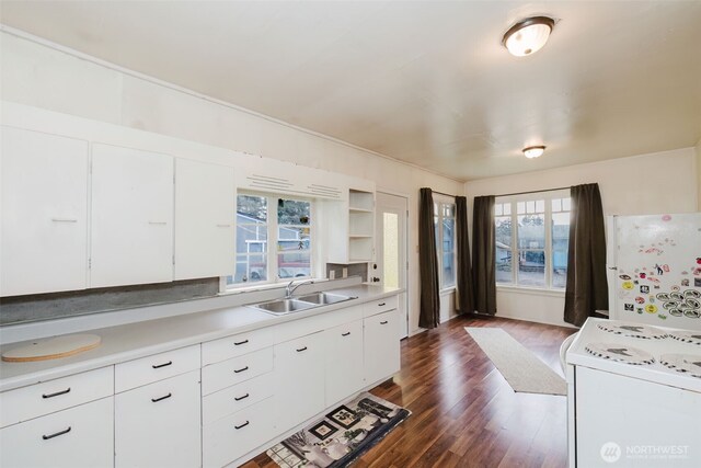 kitchen featuring white cabinets, stove, dark wood-style flooring, light countertops, and a sink