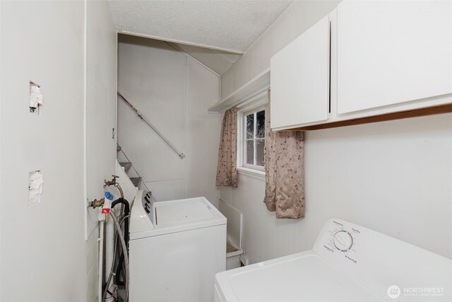 clothes washing area featuring cabinet space, independent washer and dryer, and a textured ceiling