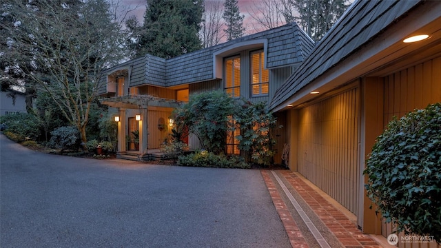 view of front of property featuring aphalt driveway, a garage, and mansard roof