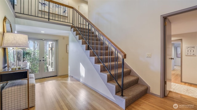 foyer entrance featuring french doors, wood finished floors, a towering ceiling, and baseboards