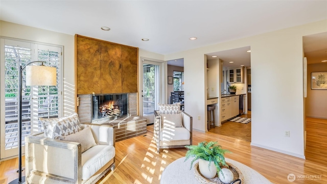 living room featuring recessed lighting, a large fireplace, plenty of natural light, and light wood finished floors