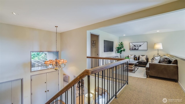 corridor featuring carpet floors, recessed lighting, a notable chandelier, and an upstairs landing