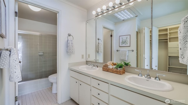 full bath featuring ornamental molding, a sink, toilet, and a shower stall