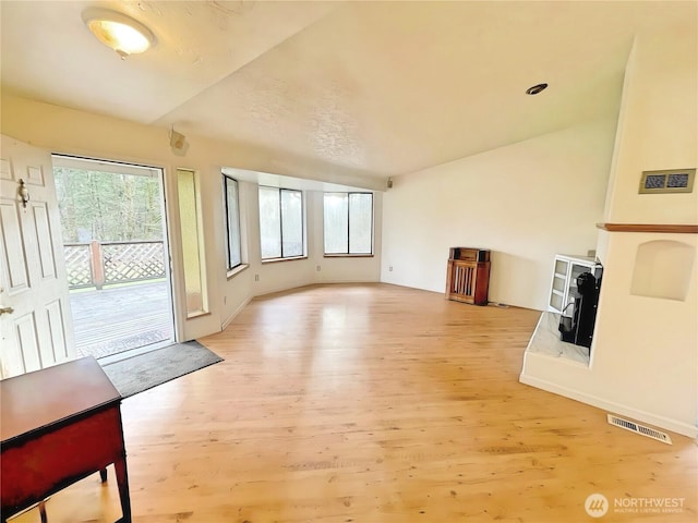 living area featuring vaulted ceiling, plenty of natural light, and light wood-style floors