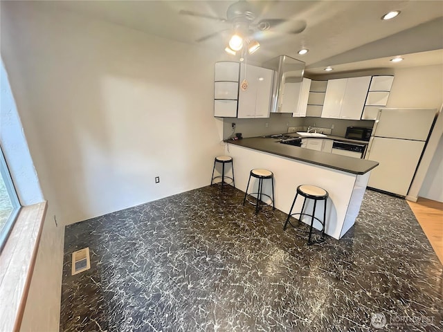 kitchen featuring dark countertops, white cabinets, modern cabinets, white appliances, and a peninsula