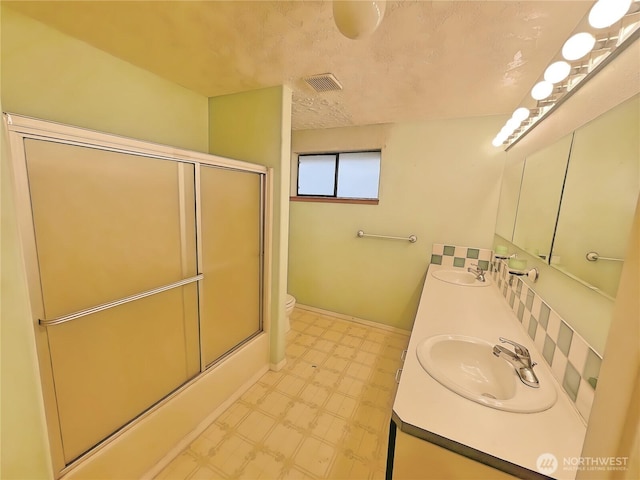 bathroom featuring toilet, enclosed tub / shower combo, a sink, and tile patterned floors