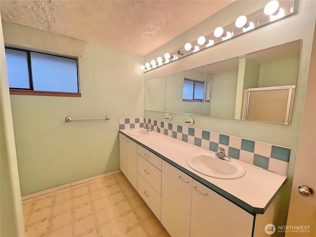 bathroom featuring a textured ceiling, decorative backsplash, a sink, and tile patterned floors