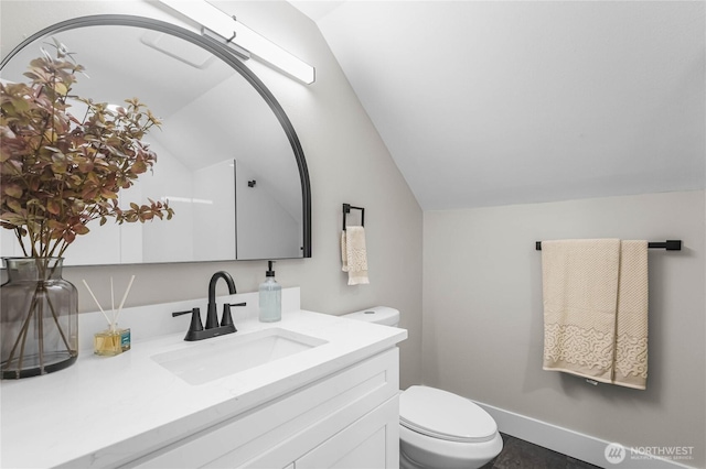 bathroom with lofted ceiling, toilet, vanity, and baseboards