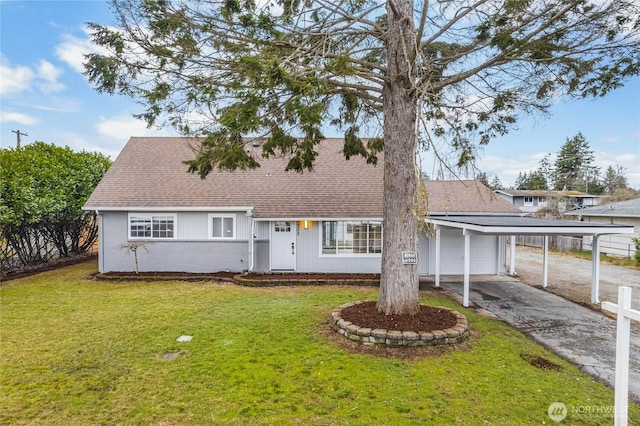 view of front facade with a carport, driveway, a shingled roof, and a front lawn