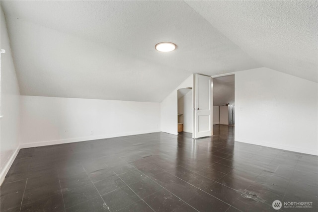 bonus room with a textured ceiling, lofted ceiling, and baseboards