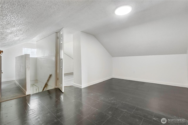 bonus room with vaulted ceiling, baseboards, and a textured ceiling