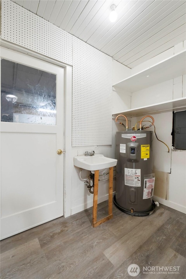 utility room with electric panel, electric water heater, and a sink